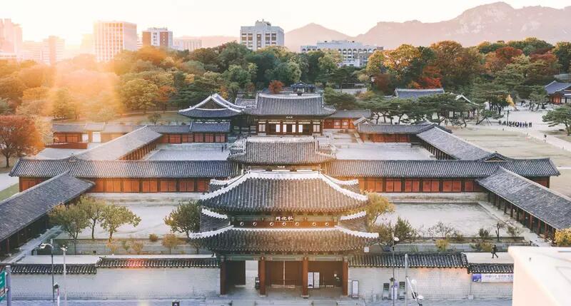 Arial photo of a palace, trees, buildings and mountains in Seoul, South Korea