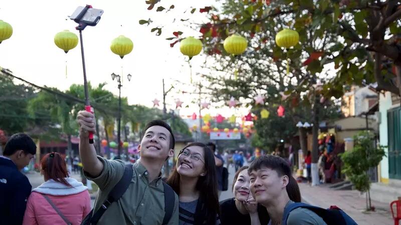 Photo of students taking a selfie in Vietnam street, with a string of yellow lanterns above