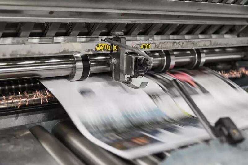 A newspaper rolling off a printing press