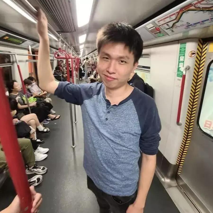 Man wearing blue shirt standing inside a subway car. 